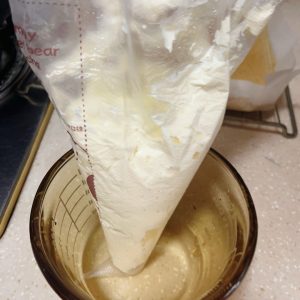 Whipped cream being spooned into a piping bag