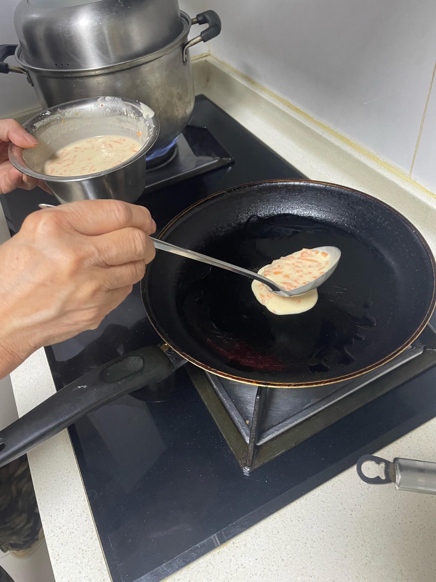 Heat a wok or non-stick skillet over low heat, spray or brush in a thin film of oil, and pour in a small ladle of batter — you should hear only a soft sizzle, never a loud hiss.