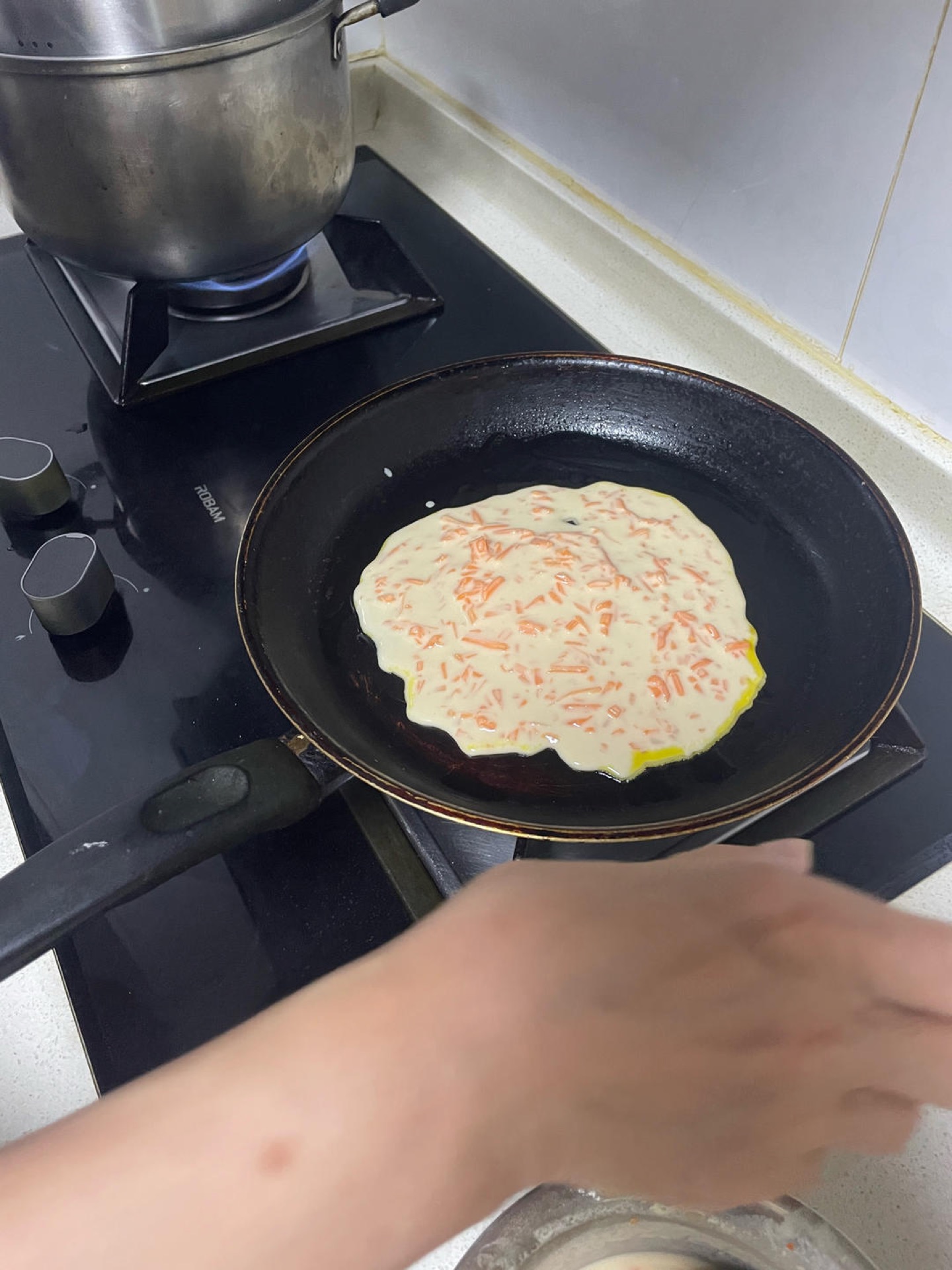 Immediately tilt the wok and use the back of the ladle to spread the batter outward into a thin, even round, working quickly before the egg sets.