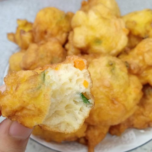Golden puffy Chinese egg puffs with scallion and carrot piled in a bowl