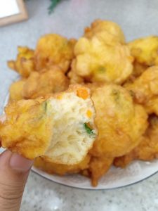 A hand reaching for warm egg puffs from a full plate