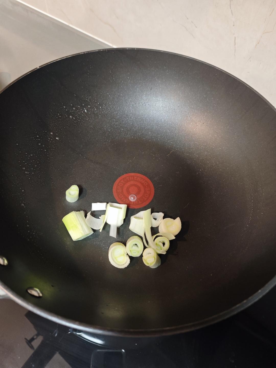 Scallion cooking in oil in the wok