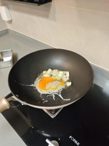Two eggs being scrambled in the wok