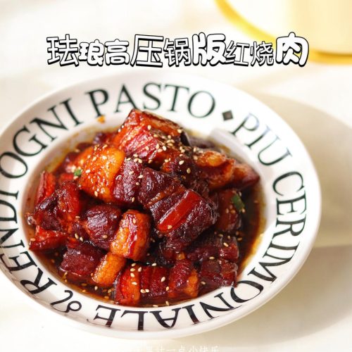 Glossy braised pork belly in an enamel pressure cooker garnished with scallions and sesame
