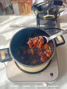 Braised pork belly reducing in the pot with sesame seeds and scallions