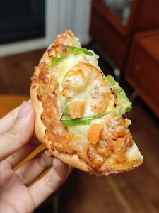 Fresh mini pizza being pulled apart showing the cheese pull