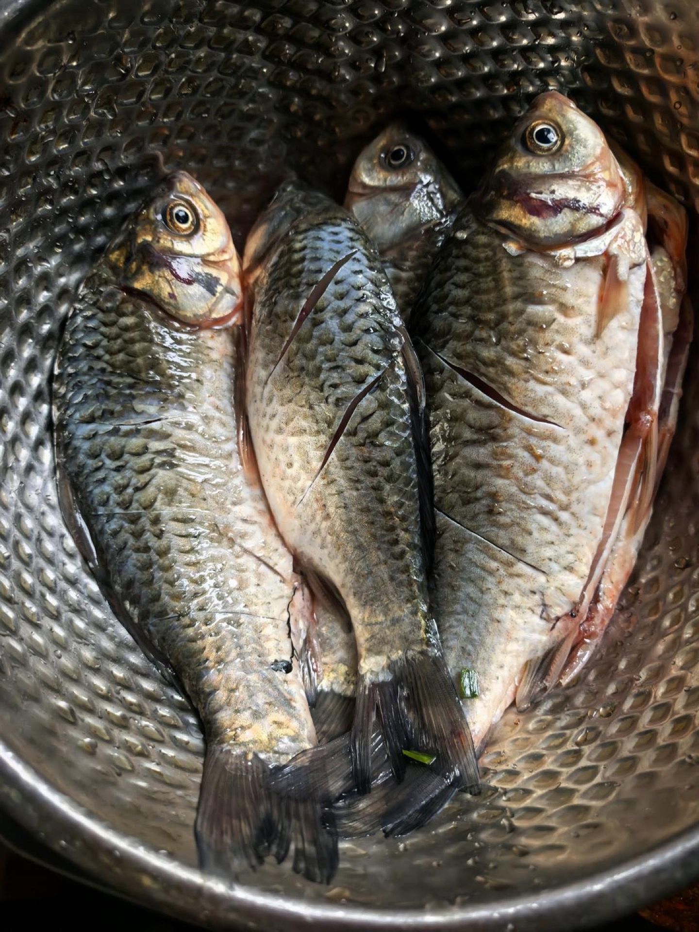 Scored and salted crucian carp resting on a board