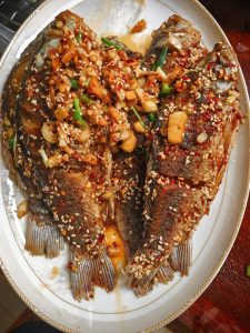 Finished fried crucian carp plated with chili and scallion