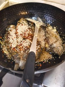 Fried fish returned to the wok with aromatics