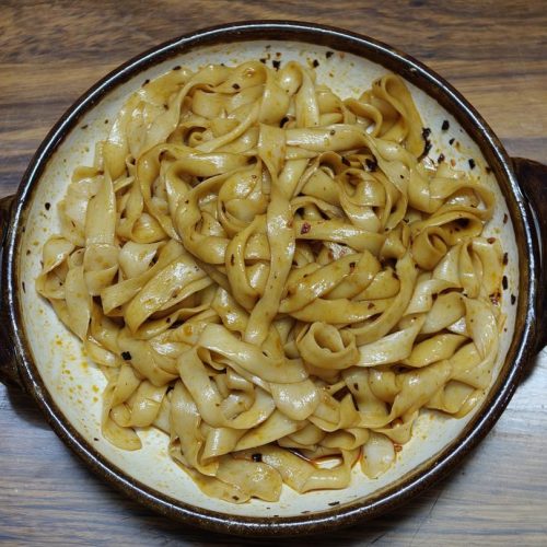 Bowl of hand pulled noodles tossed with chili oil and scallion