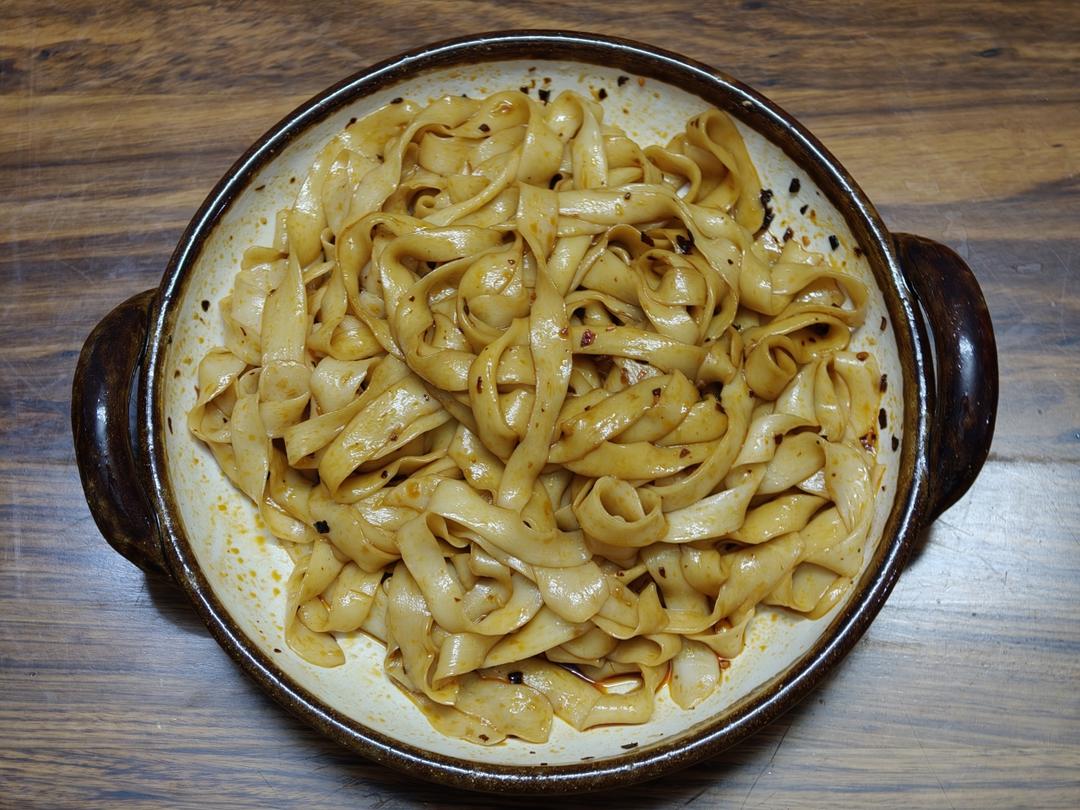 Pouring hot oil over chili flakes and scallion on the noodles