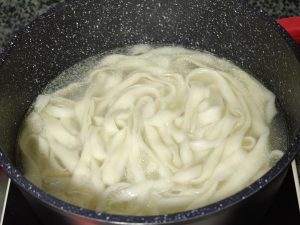 Stretching an oiled strip and dropping noodles into boiling water