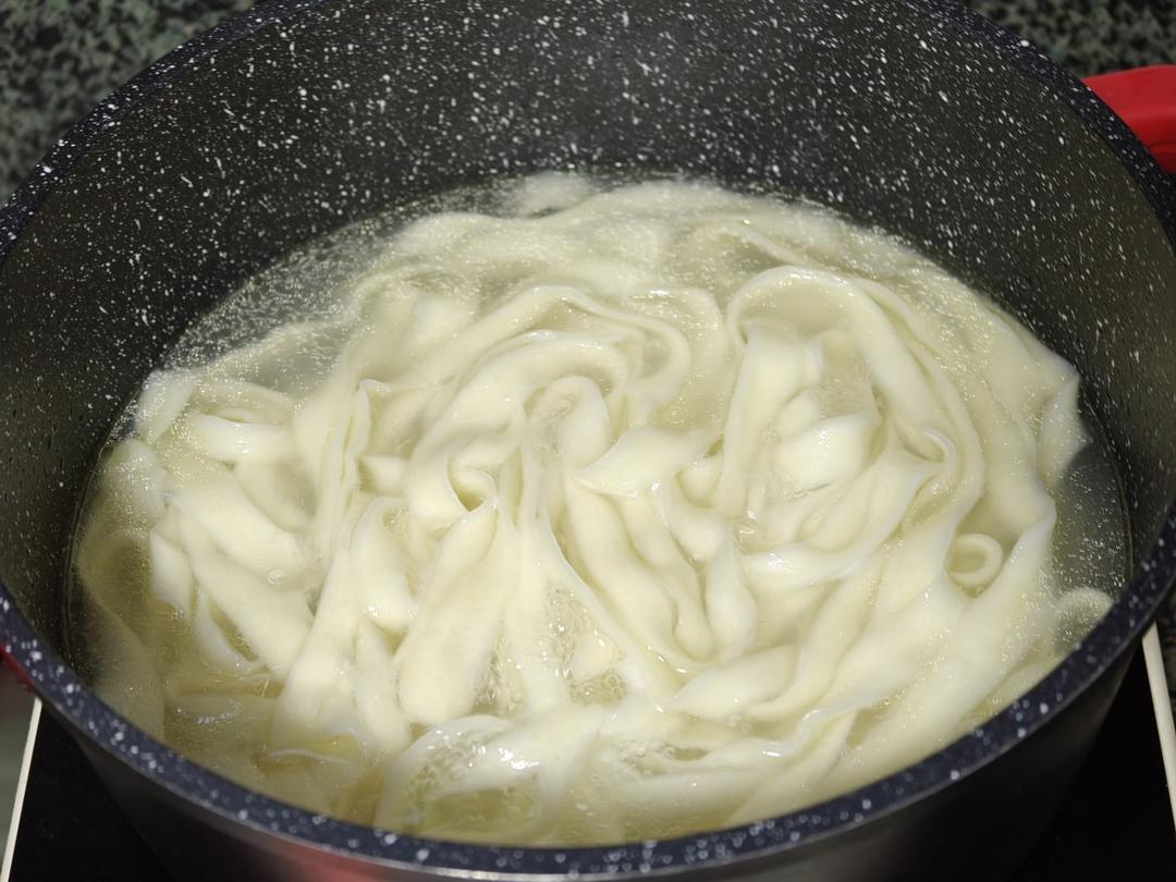 Stretching an oiled strip and dropping noodles into boiling water