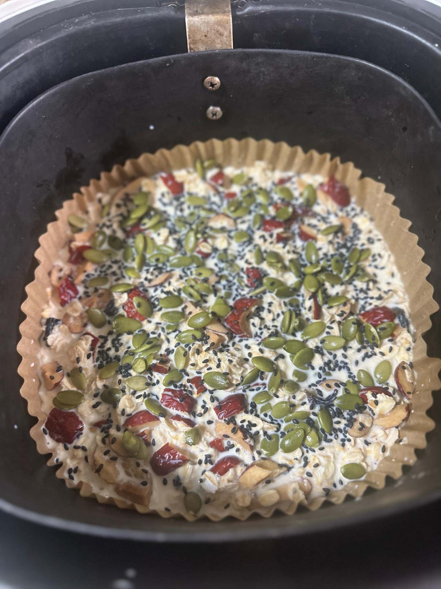 Unbaked oat cake topped with walnuts and black sesame in a pan