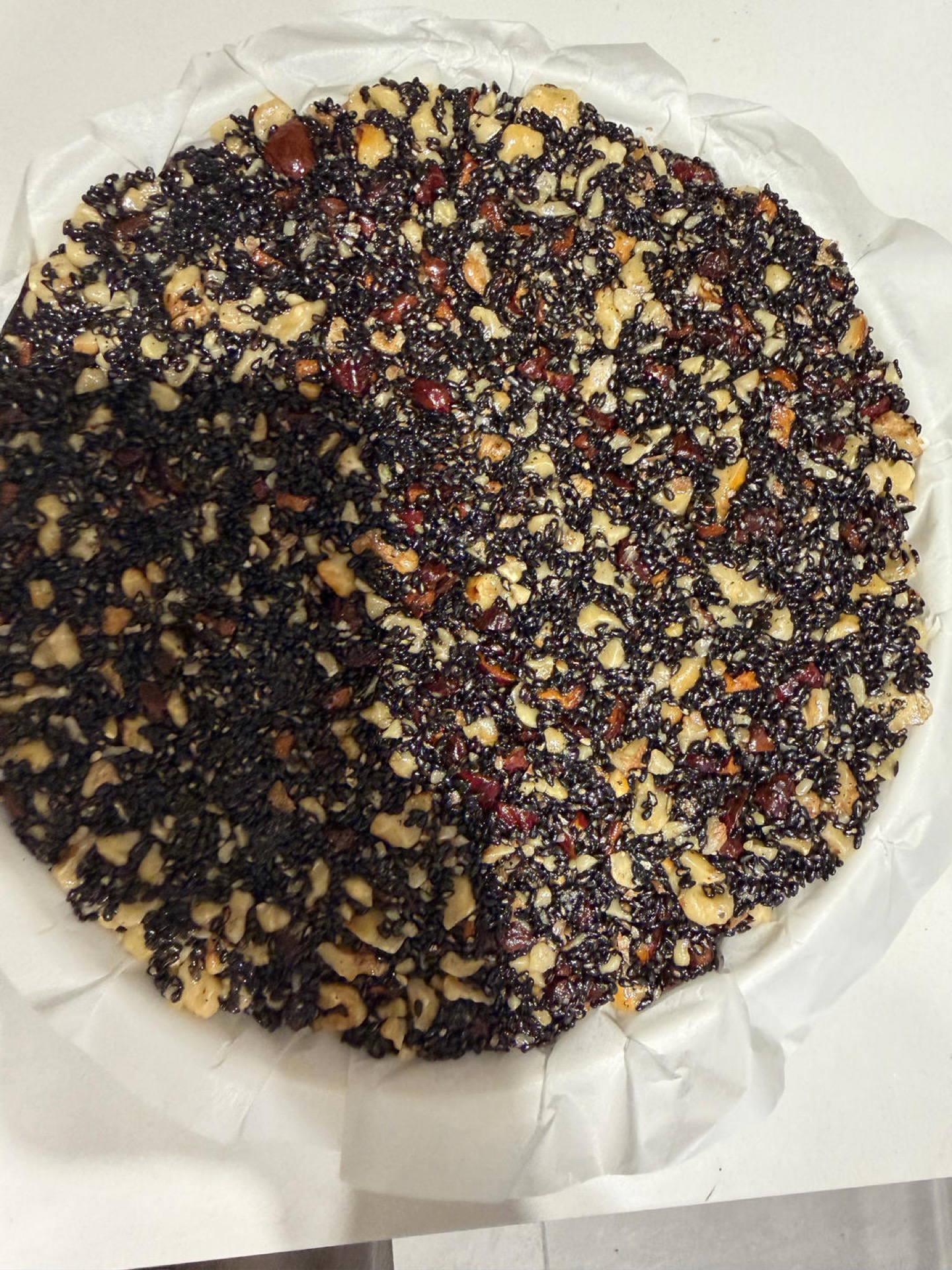 Sesame date mixture pressed flat on a lined plate