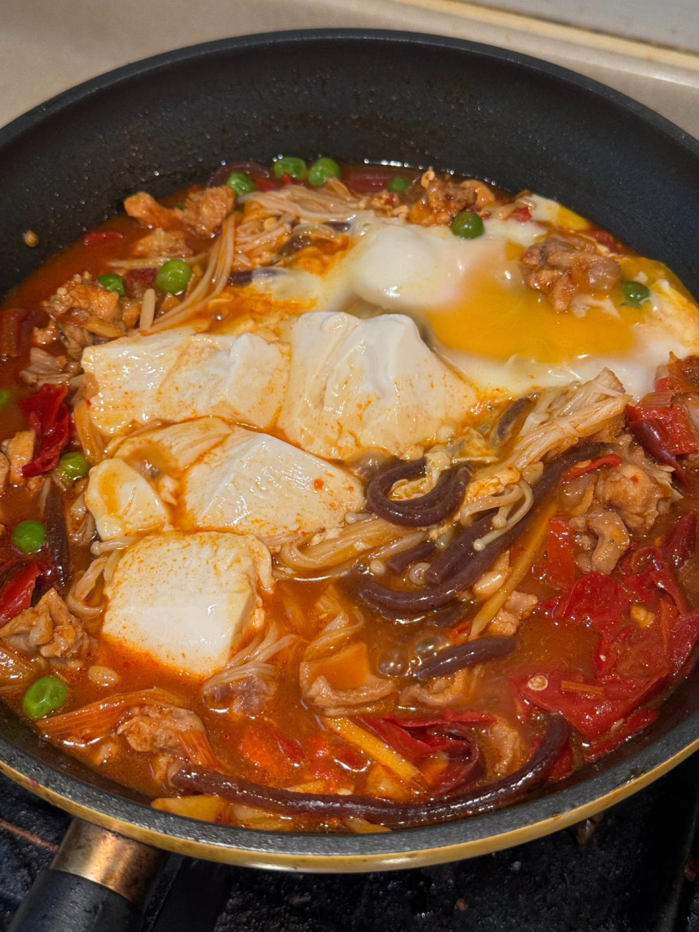 Enoki mushrooms and soft tofu added to the simmering broth