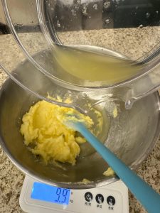 Stirring lemon juice into the creamed butter