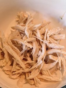 Hand-shredded chicken breast strips in a bowl
