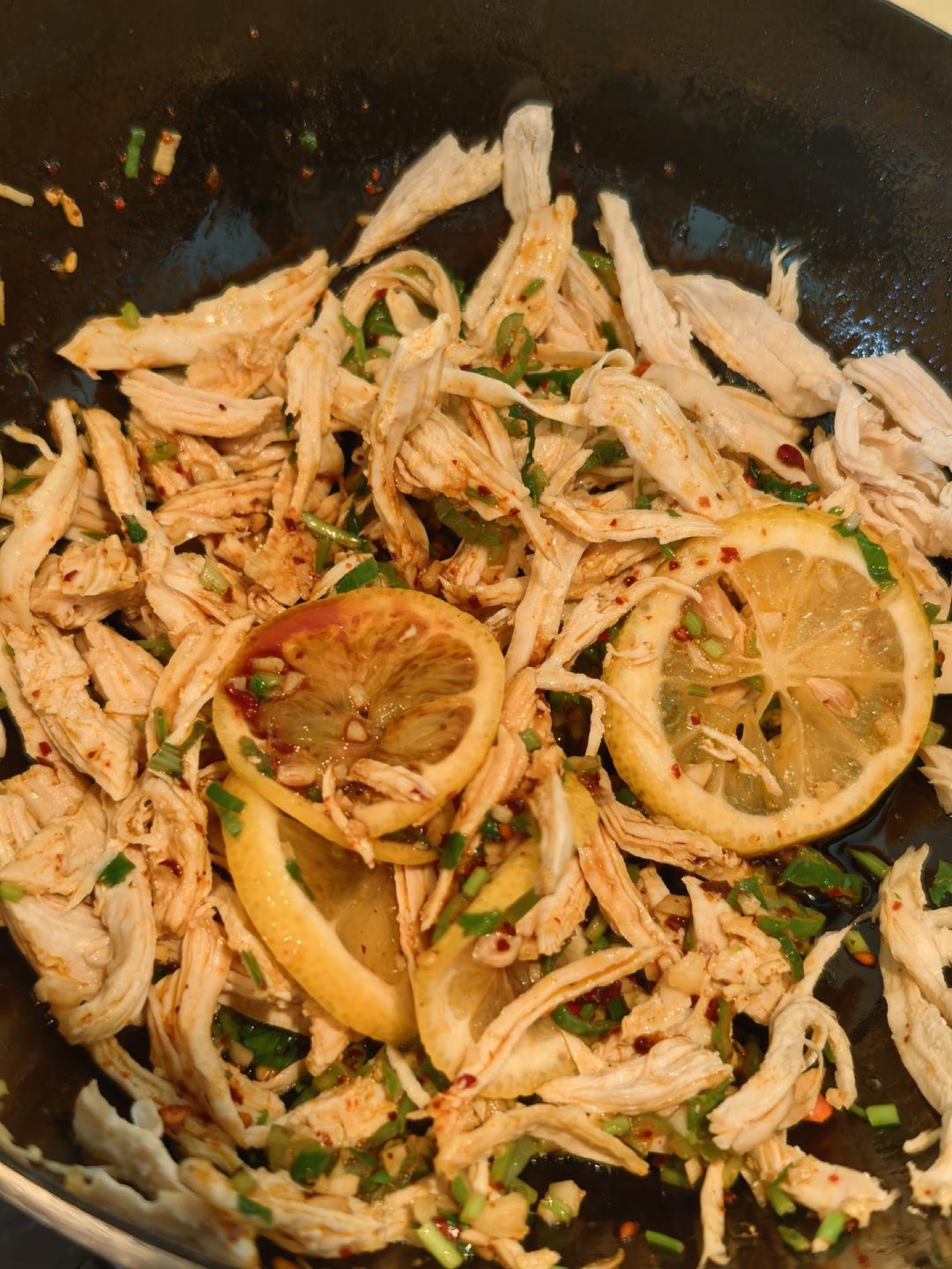 Hot oil being poured over aromatics and shredded chicken