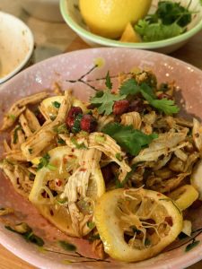Finished lemon shredded chicken breast garnished with cilantro, peanuts, and lemon