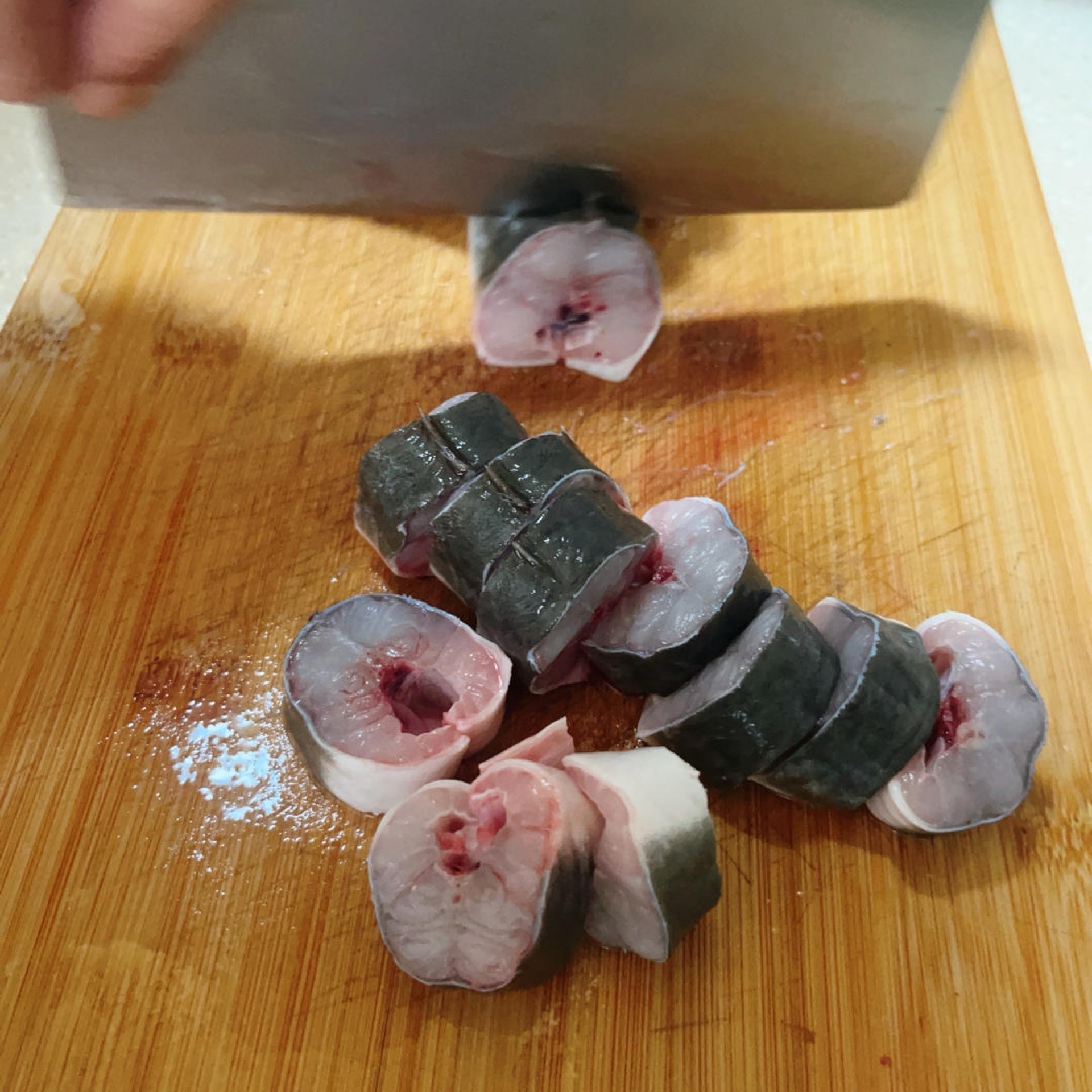 Eel pieces marinating in a bowl with aromatics