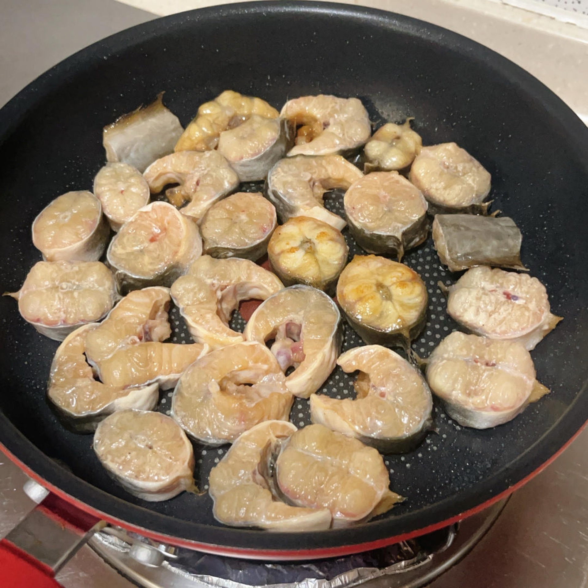 Seared eel pieces turning golden in the wok