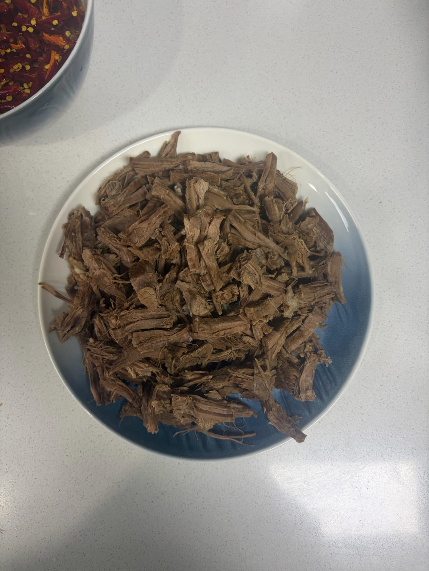 Once the beef has cooled, tear it along the grain into strips (this part takes some patience).