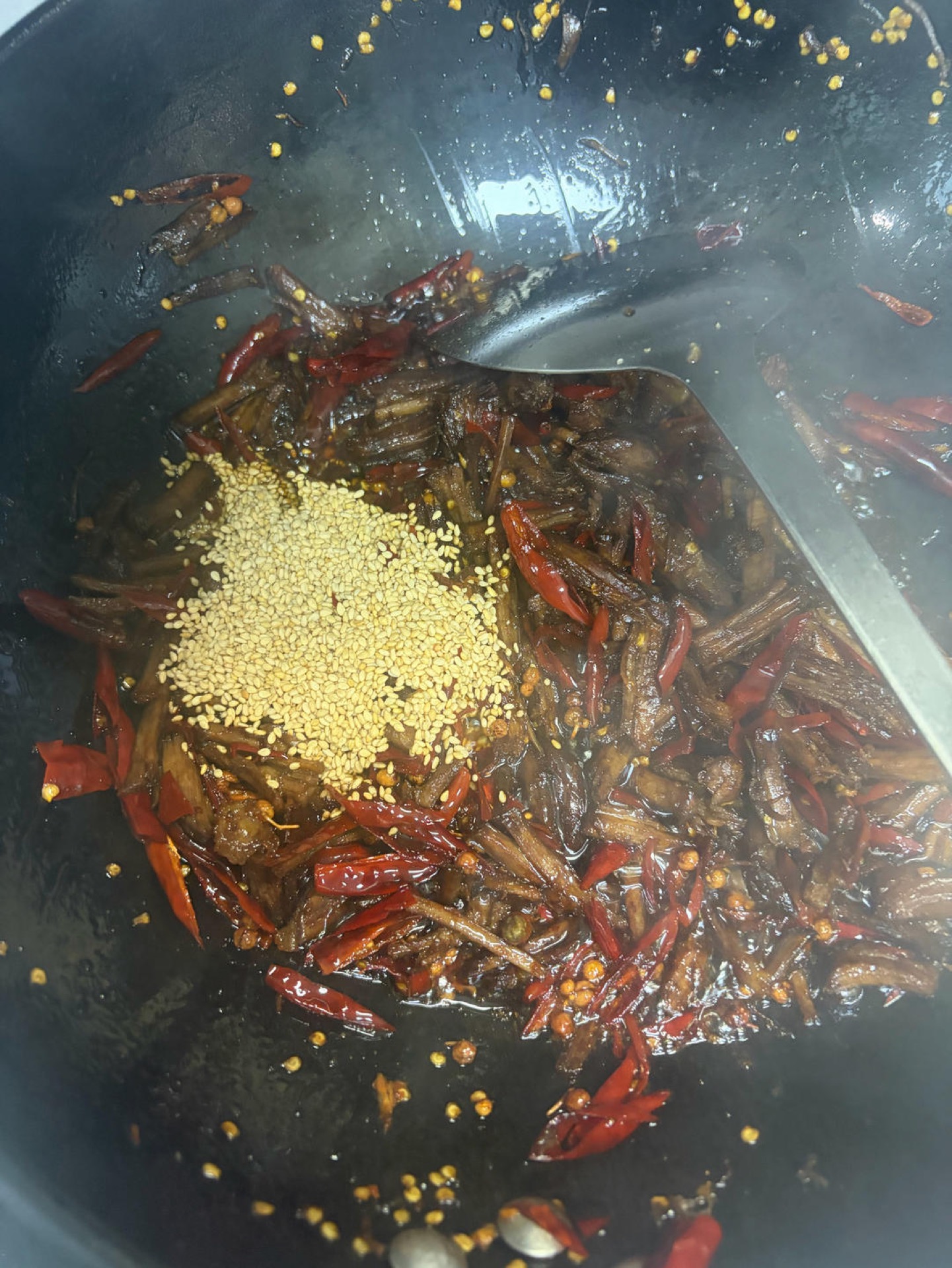 After removing the aromatics, add the shredded beef to the wok and stir-fry for 2-3 minutes, then add the soaked chilies and Sichuan peppercorns. After a few stirs, lower the heat