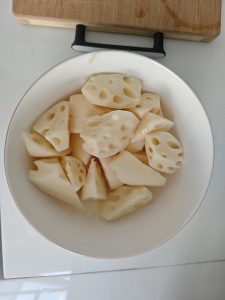 Lotus root chunks tossed with salt and sugar in a bowl