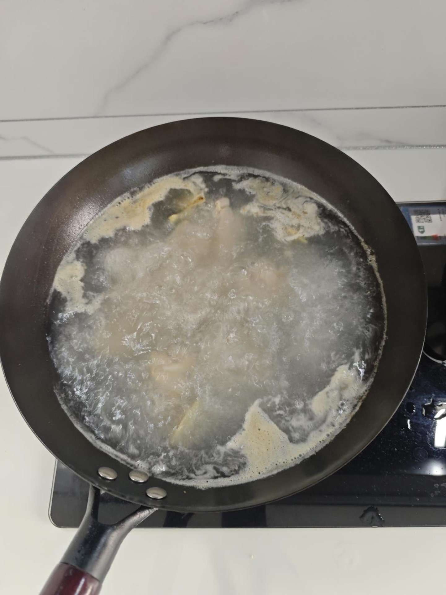 Milky white pork rib broth boiling in a pot