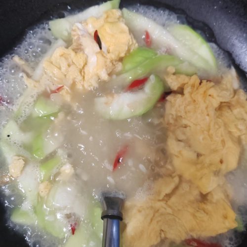 A bowl of luffa and egg soup with silky luffa chunks in a milky egg broth, garnished with scallions
