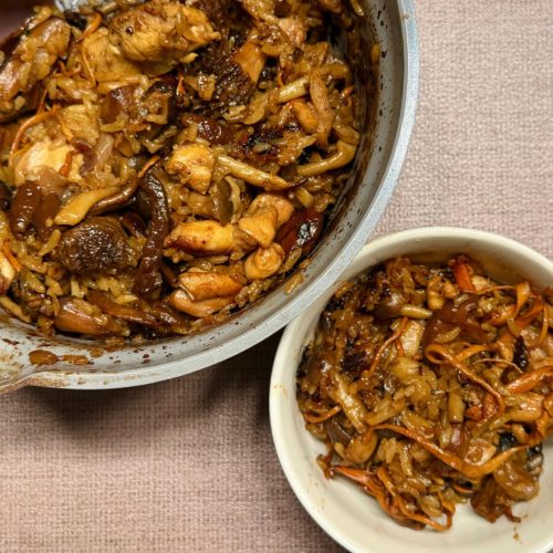 Mushroom chicken claypot rice in a wok, garnished with scallions