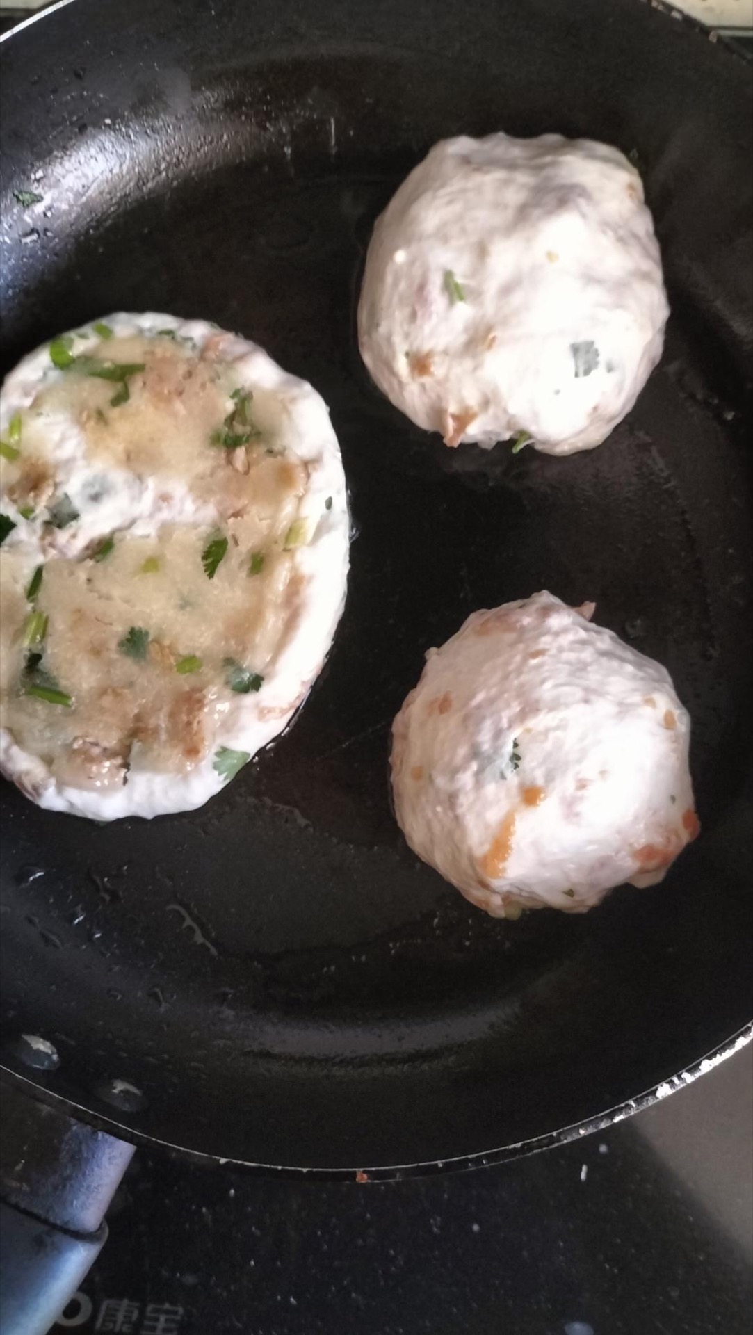 Wet hands pinching off a piece of dough and wrapping pork inside