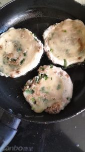 Flipping a meat pie in the pan and pressing it flat with a spoon