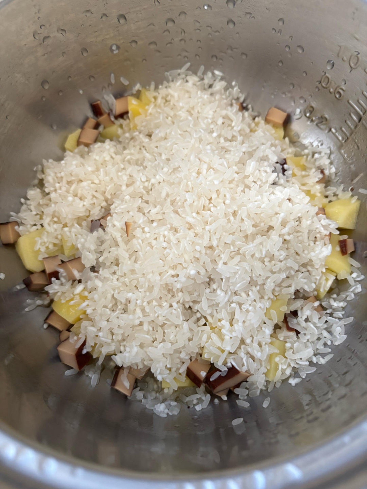 As soon as the switch flips to warm, lift the lid and pour in the rinsed rice — rinsing it and soaking it for half an hour beforehand gives an even fluffier result.