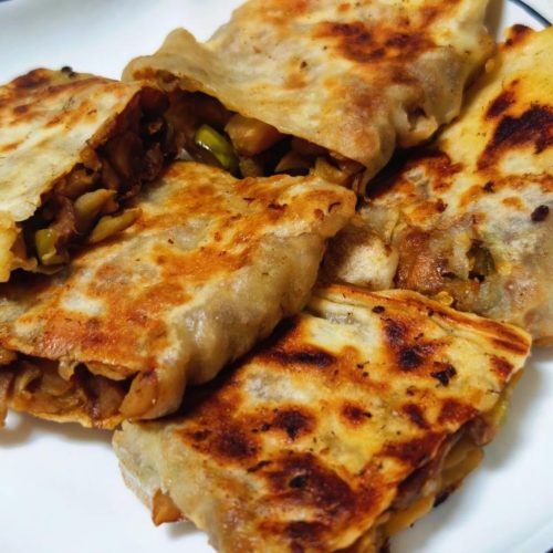 Pan-fried eggplant dumplings with crispy golden bottoms stacked on a plate