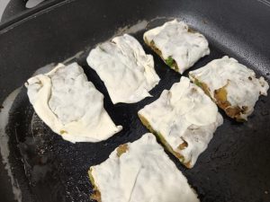 Brush a layer of oil into a flat-bottomed pan, turn on medium heat, and put the pieces in.