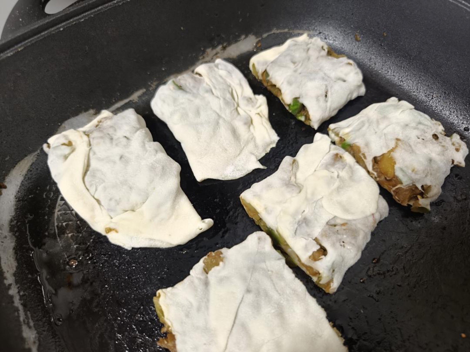 Brush a layer of oil into a flat-bottomed pan, turn on medium heat, and put the pieces in.