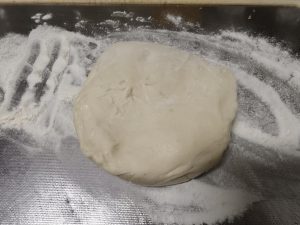 Next, sprinkle dry flour over the cutting board and put the dough on the board. If the dough is too big, cut it into smaller pieces.