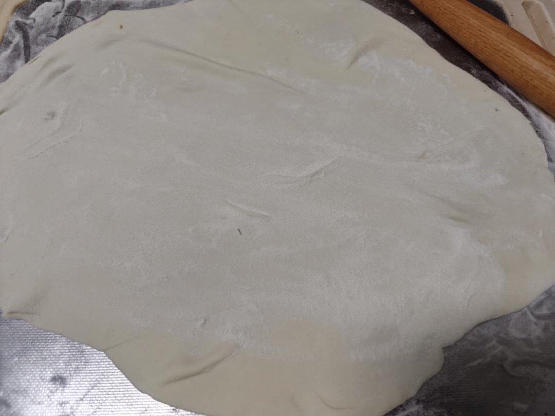 Then roll it into thin sheets (while rolling, there must be dry flour on both the top and bottom so it does not stick — you can flip and roll both sides).