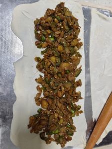 Spread plenty of eggplant filling over the upper half of the dough sheet (you can also spread filling over the whole sheet and cover it with the other half — that just makes a bigg