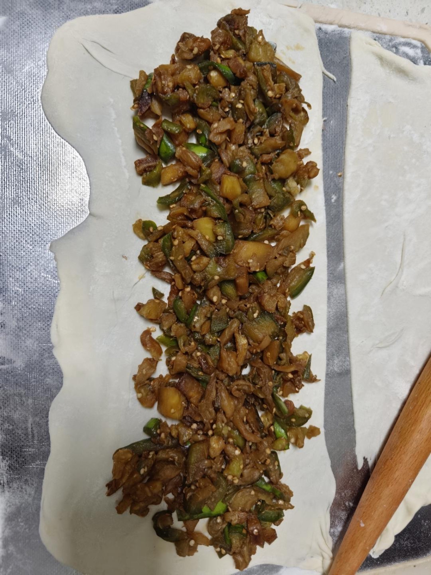 Spread plenty of eggplant filling over the upper half of the dough sheet (you can also spread filling over the whole sheet and cover it with the other half — that just makes a bigg