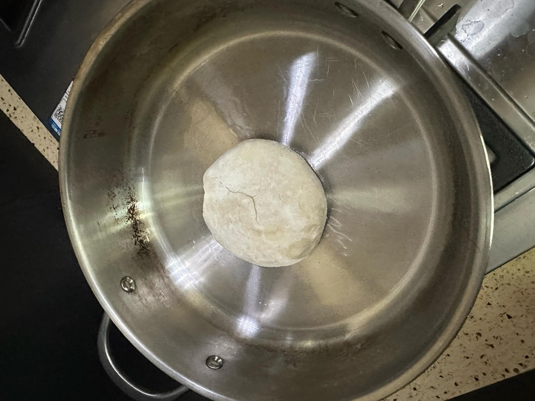Dough being pressed flat by hand on the griddle