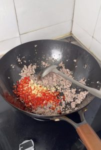 Adding garlic and chili to the frying pork