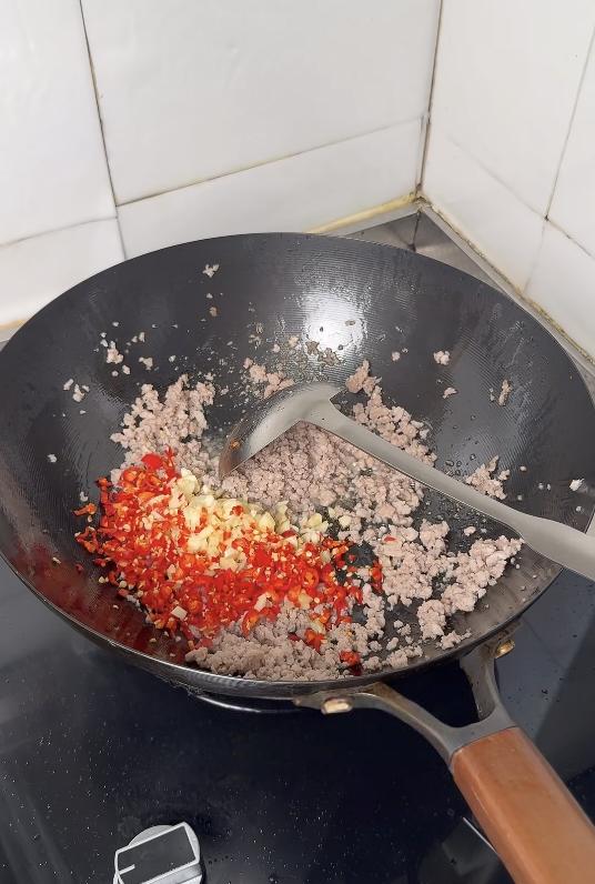 Adding garlic and chili to the frying pork