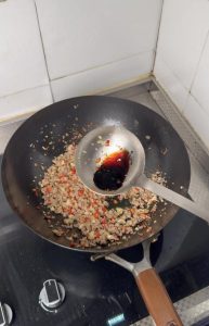Adding dark soy sauce to the pork
