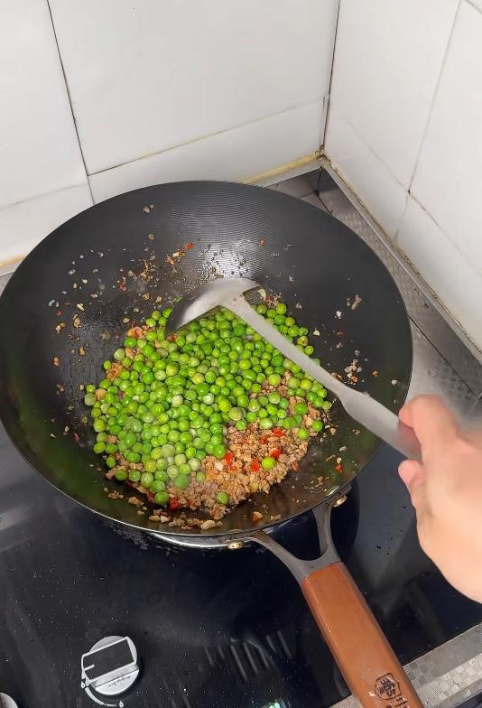 Adding the blanched peas to the pork