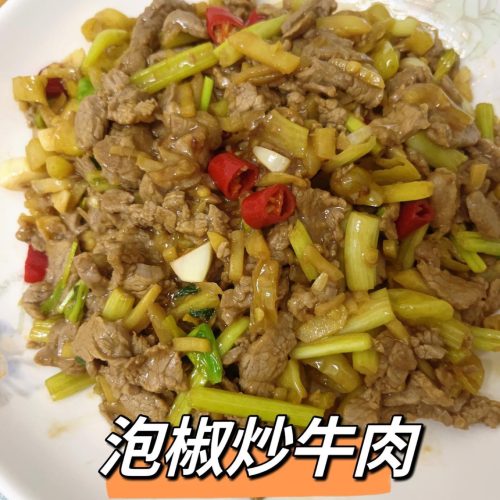 Pickled pepper stir-fried beef with tender beef slices, pickled chilies, and celery served on a white plate