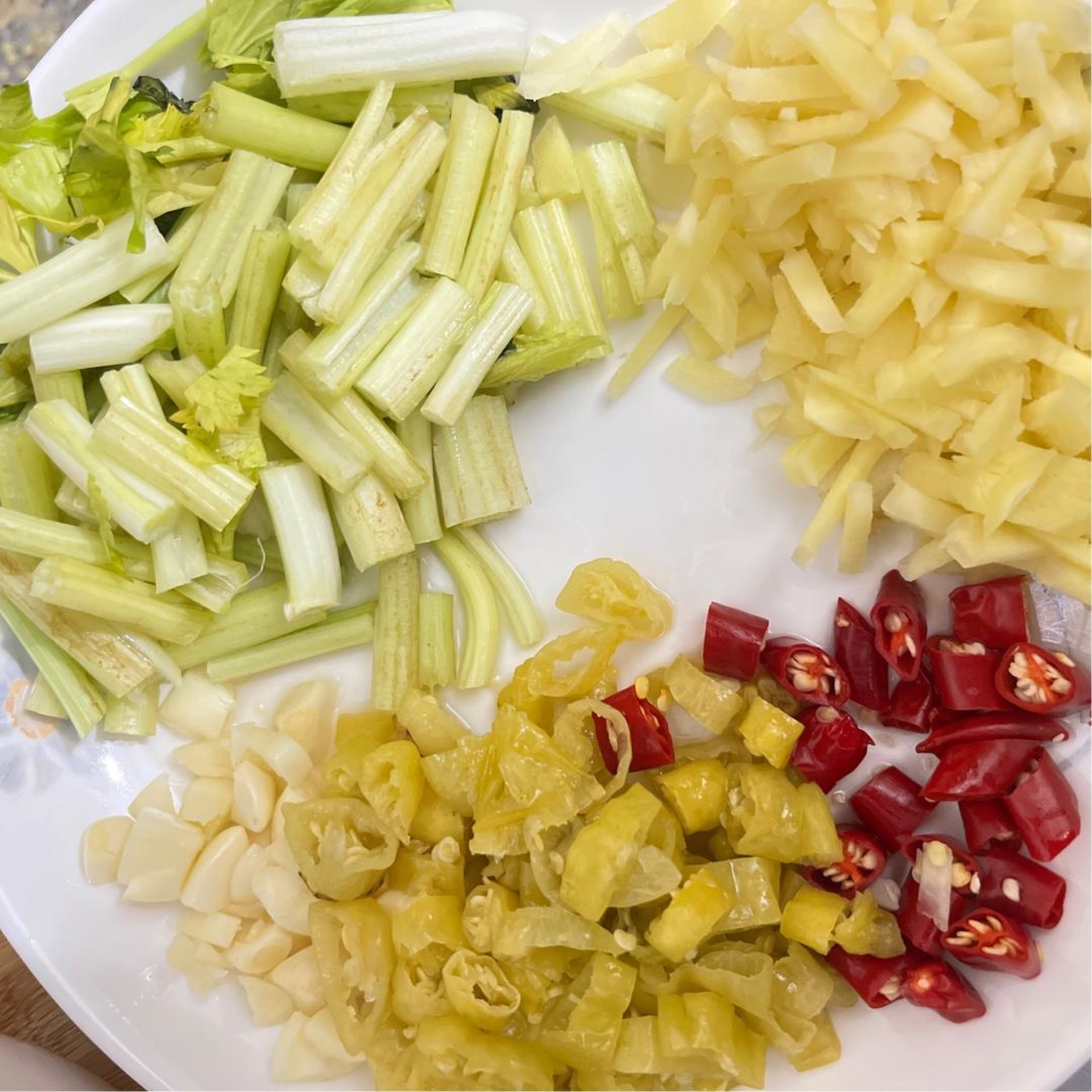Slice the bird's eye chilies, pickled chilies, young ginger, and garlic, and cut the celery into short batons, keeping the leaves separate.