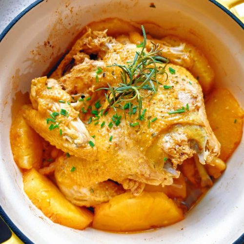 Pineapple roasted chicken 菠萝霸王鸡 in a pot surrounded by golden pineapple rings and scattered scallions